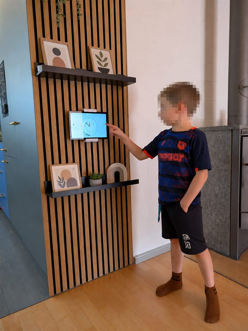 Ein grösseres Kind schaut an der Wand-Lernuhr auf seine Routine und den nächsten Schritt